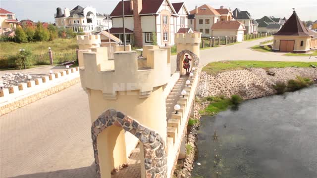 Cottage village, stylized old bridge with turrets Bridge, towers, road, pond, cottages