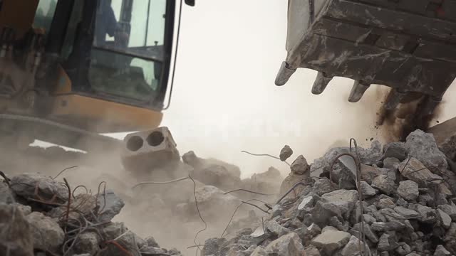 An excavator rakes through the rubble at the site of a demolished building Excavator, construction...
