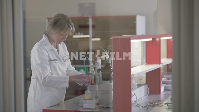 Эксперт проверяет жидкость в мерном стакане Лаборатория, экспертиза, люди, женщины, мерный стакан,...