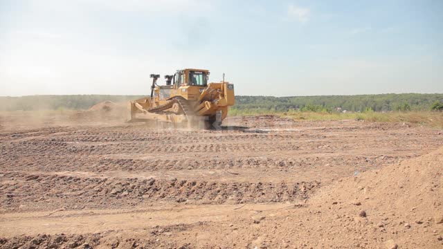 The bulldozer rakes the ground, clears and levels the site Bulldozer, road equipment, earth, clay