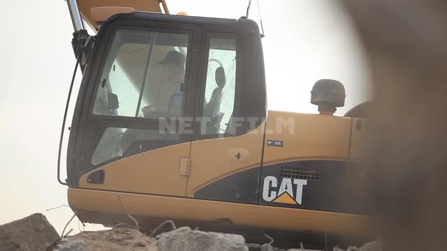 Excavator with a narrow bucket rakes the blockage, the driver in the cab Excavator, construction...