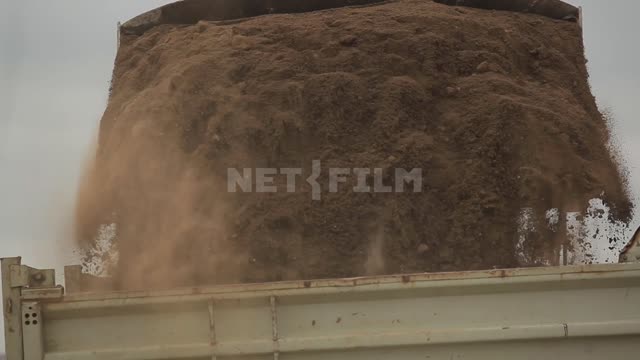 A bulldozer pours earth into the back of a dump truck Bulldozer, dump truck, truck, body, road...