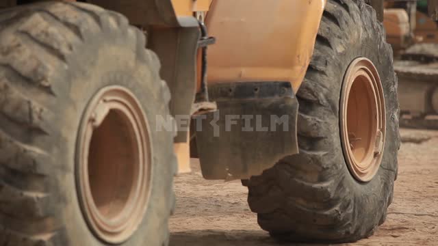 The bulldozer maneuvers on the site Bulldozer, road equipment, wheels, bucket, stones, pieces of...
