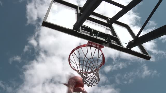 Баскетбол, игрок забивает мяч в корзину Баскетбол, мяч, щит, корзина, сетка, рука, спорт, облака