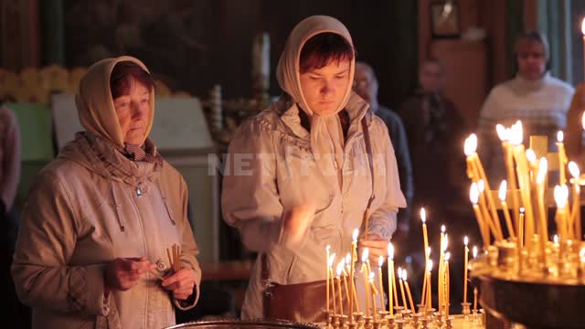 Trinity-St. Sergius Lavra, a woman lights a candle, puts it on the altar, crosses herself...