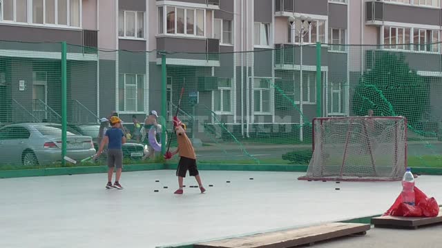 На хоккейном поле два мальчика бьют клюшками по шайбам в ворота. Лед, хоккей, разминка, дети,...