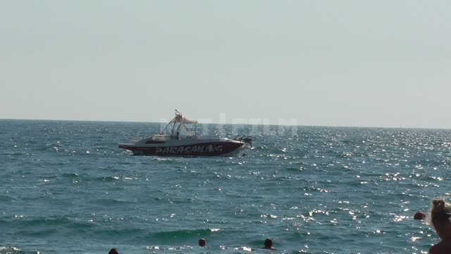 black sea, a boat with the inscription "Parachute" swings on the sea waves people swim in the sea...