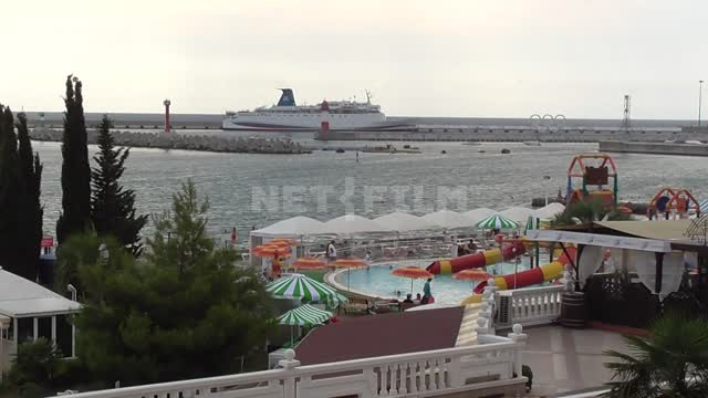 Аквапарк на берегу черного моря, с горок катаются дети, плавают в бассейне, в море стоят яхты,...
