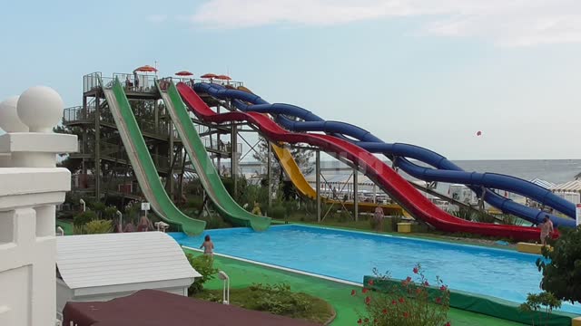 Water park, colorful slides from which children ride, the black Sea on the background Water park,...