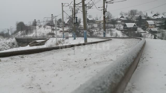 Snow-covered railway on the background of the village Winter, rails, railway, road, station,...