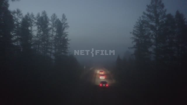 Ночь, сумерки, туман, по дороге едут машины, дорога освещена светом фар (снято с коптера) Туман,...