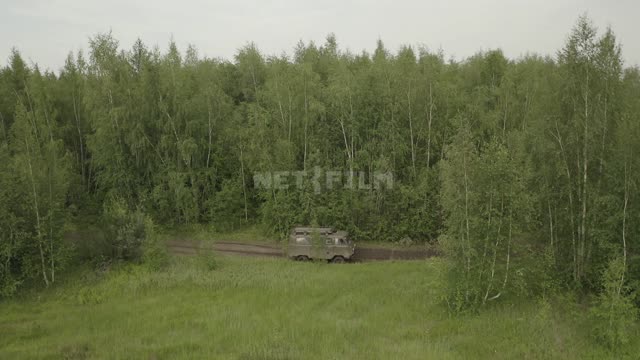 Лес, поляны, по проселочной дороге едет зеленый военный грузовик, в кадре небольшие озера, деревья...