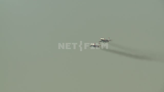 Два самолёта пилотажной группы "Стрижи" в небе показывают  фигуры пилотажа. Самолеты истребители