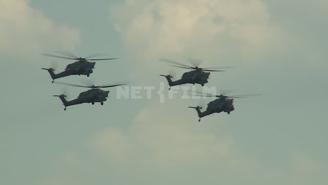Four helicopters perform aerobatics. Military helicopters