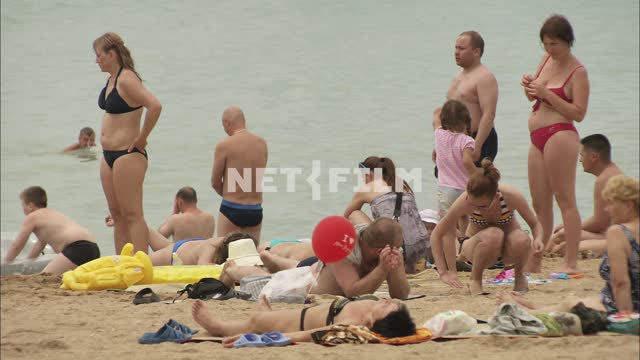 People resting on the beach General plan.
Sea.
People are...