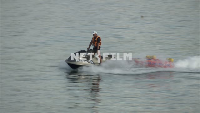 A jet ski pulls a rubber boat. Transport.
Lifeguard.
Sea.
Summer.
Day.