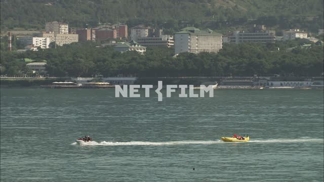 A jet ski pulls a rubber boat with people. Transport.
Sea.
Rest.
Summer.
Day.