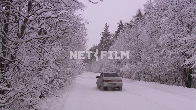 Легковой автомобиль едет по заснеженной дороге. Транспорт
День
Зима
Снег
Лес
Дорога 
Деревья в снегу