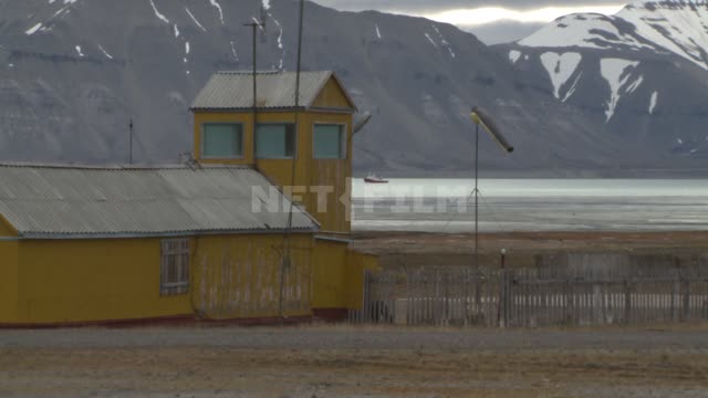 Wooden building near the helipad. Russian North, mountains, snow, helicopter, supplies a wind sock.