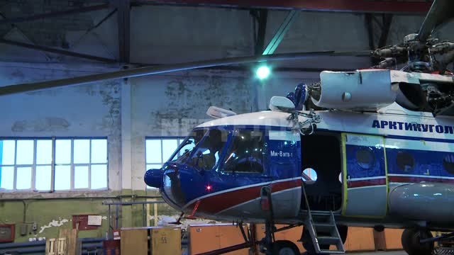 Mechanics inspect the MI-8 helicopter in the hangar. Russian North, hangar, helicopter, blades,...
