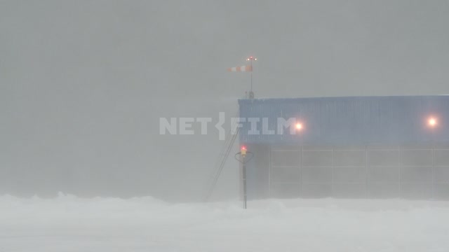 Supplies a wind sock in a Blizzard on the roof of the hangar for a helicopter. Russian North,...