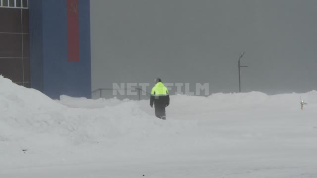 The man walks through the snow to the hangar. Russian North, snow, snow man, Blizzard hangar.