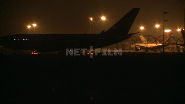 Night airfield tractor tows a plane on the tarmac. Airport, takeoff, airplane, spotlight, lights,...