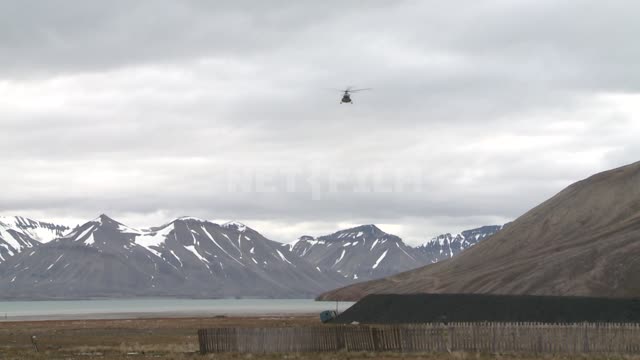 The helicopter flies over the mountains and sits on the landing pad. Russian North, helicopter,...