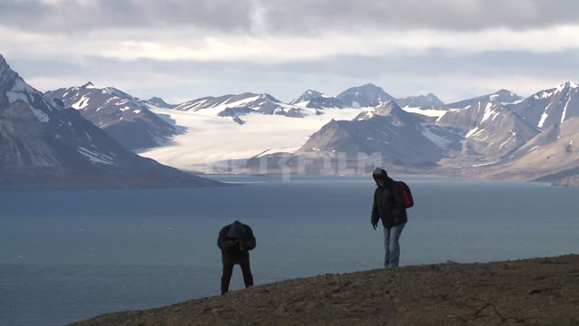 Туристы на холме на фоне моря и гор. Русский север, море, горы, туристы, фотоаппарат, снег.