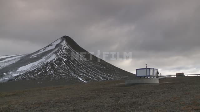 Вид на горный пик и жилой модуль. Русский север, гора, домик, снег, вершина.