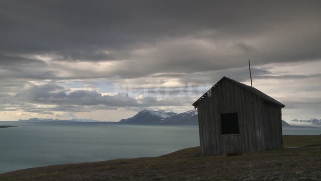 Wooden house on the beach Russian North, sea, coast, home, mountains, clouds.
