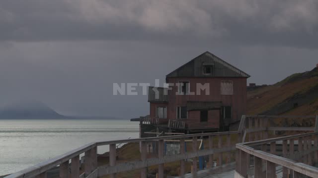 Wooden house on the shore. Russian North, house, sea, mountain, railing, bridges, clouds, clouds.