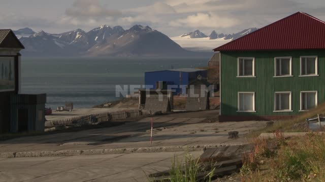 Вид на здания на берегу на фоне моря и гор. Русский север, здания, море, горы, пешеходы, снег,...