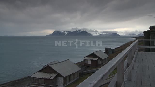 View of wooden houses on the shore, the sea and the mountains. Russian North, railings, beach...