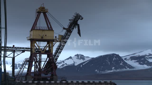 Crane on the background of the mountains in the port of Barentsburg.
 Russian North, crane,...