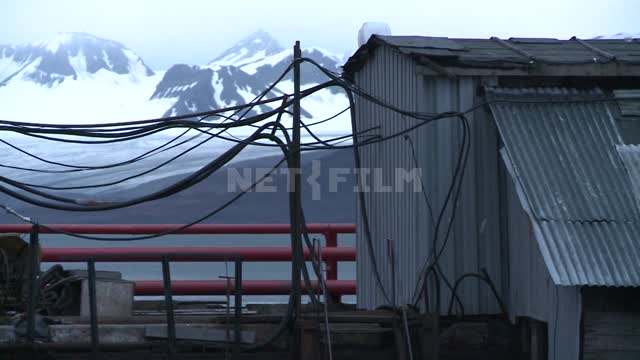 Pan with iron boxes power substation standing on the dock at the snow-capped mountains. Russian...