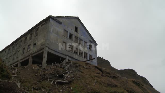 Вид снизу на стоящее на холме брошенное административное здание на сваях. Русский север, знание,...