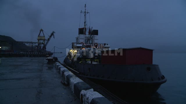 The tug is moored. Russian North, tug, berth, pier, evening, lights, sea, boat.