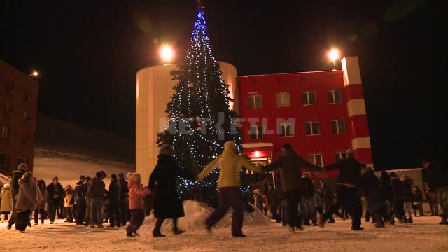 People in the area drive Christmas dancing around the Christmas tree. Russian North, fir tree,...