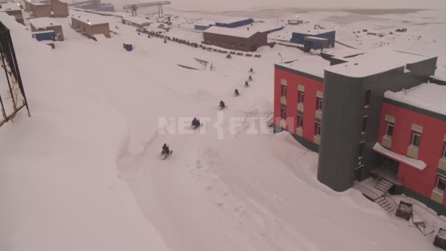 Колонна людей на снегоходах движется по дороге. Русский север, зима, снег, автосани.