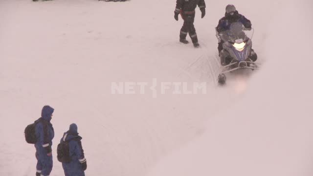 Колонна людей на снегоходах выезжает с паркинга. Русский север, зима, снег, автосани.
