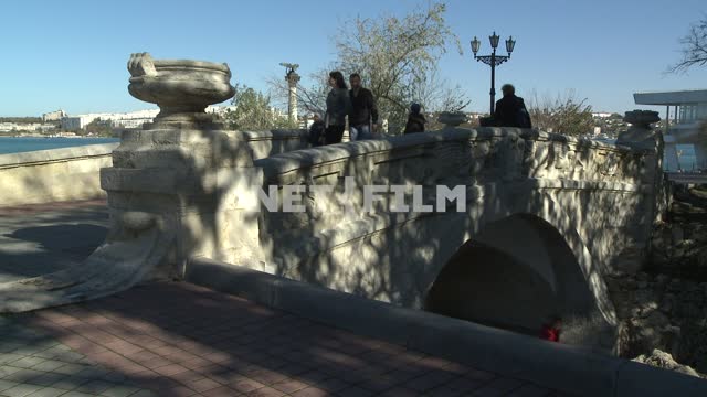 Люди проходят по каменному мосту в Севастополе...