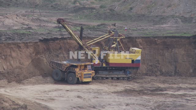 Excavator loads the rock body mining dump truck BelAZ-75170. Bucket, excavator, dump truck, quarry,...