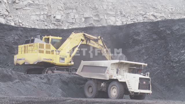 Komatsu excavator loads the rock body dump truck Terex. Bucket, excavator, dump truck, quarry, coal.