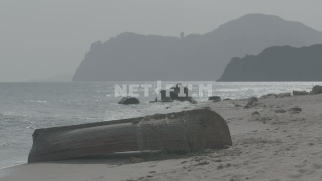 Wooden boat on the seashore Mountains, rocks, sea, beach, boat, chain, waves, sand.