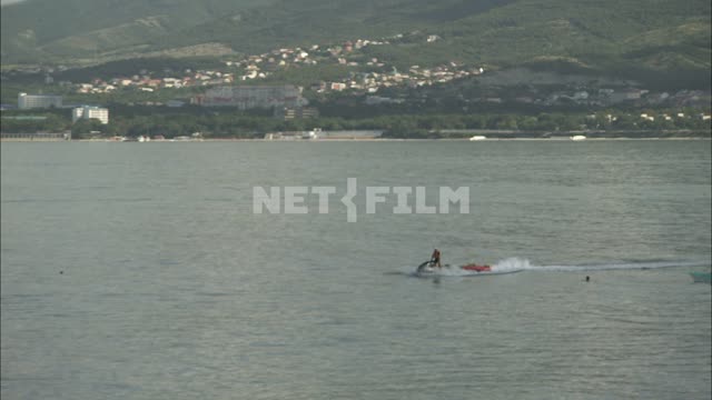 Мужчина на гидроцикле  плывет вдоль берега. Водный мотоцикл, гидроцикл, берег, море, волны.